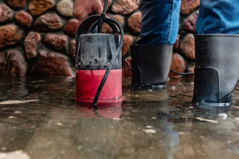Ein Mann pumpt mit einer Tauchpumpe Wasser ab.
